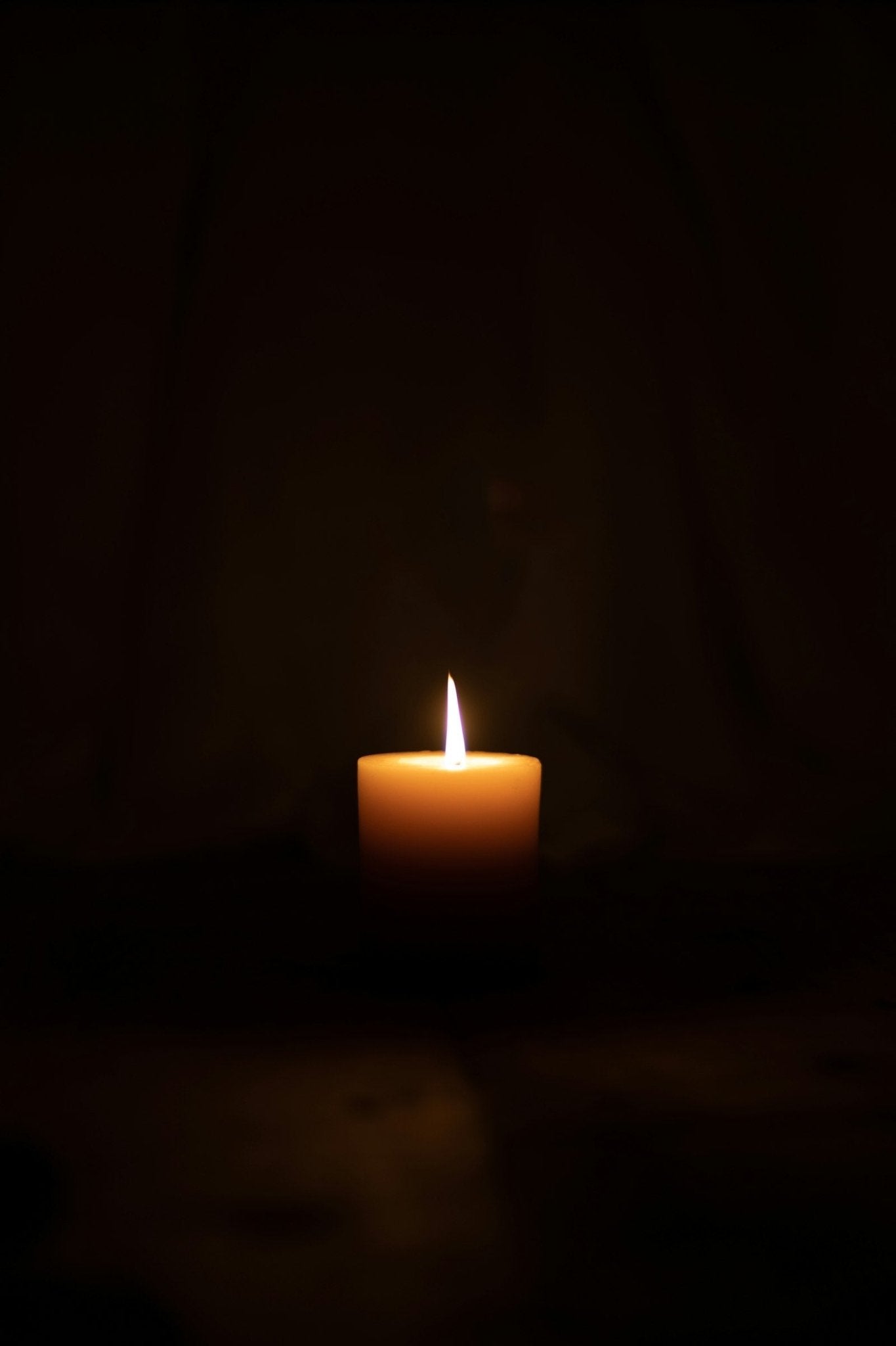 A lighted candle burning in a dark room