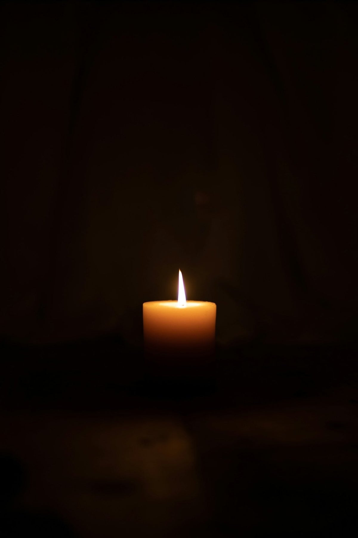 A lighted candle burning in a dark room