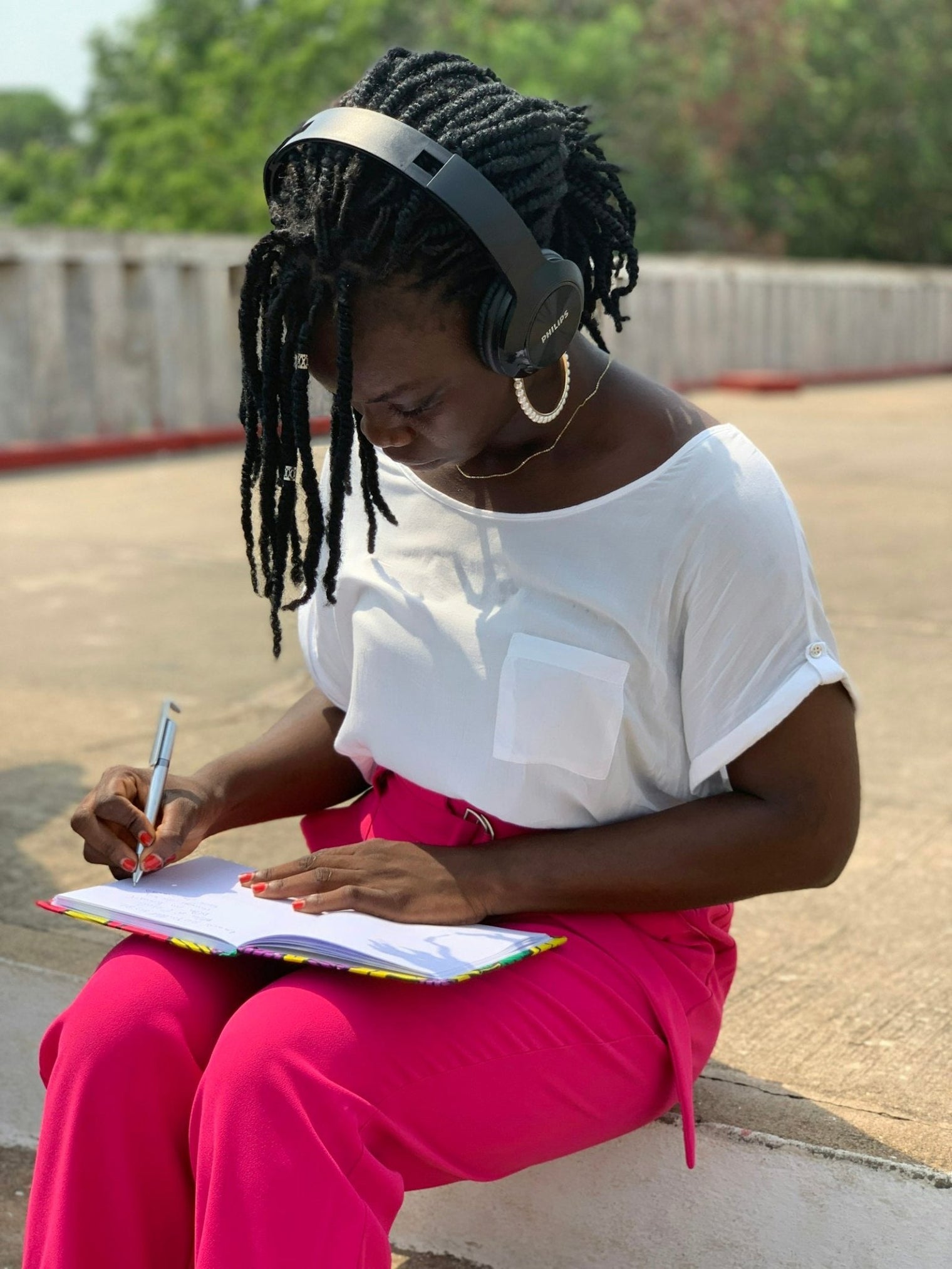 A Black woman writing in a notebook with a pen