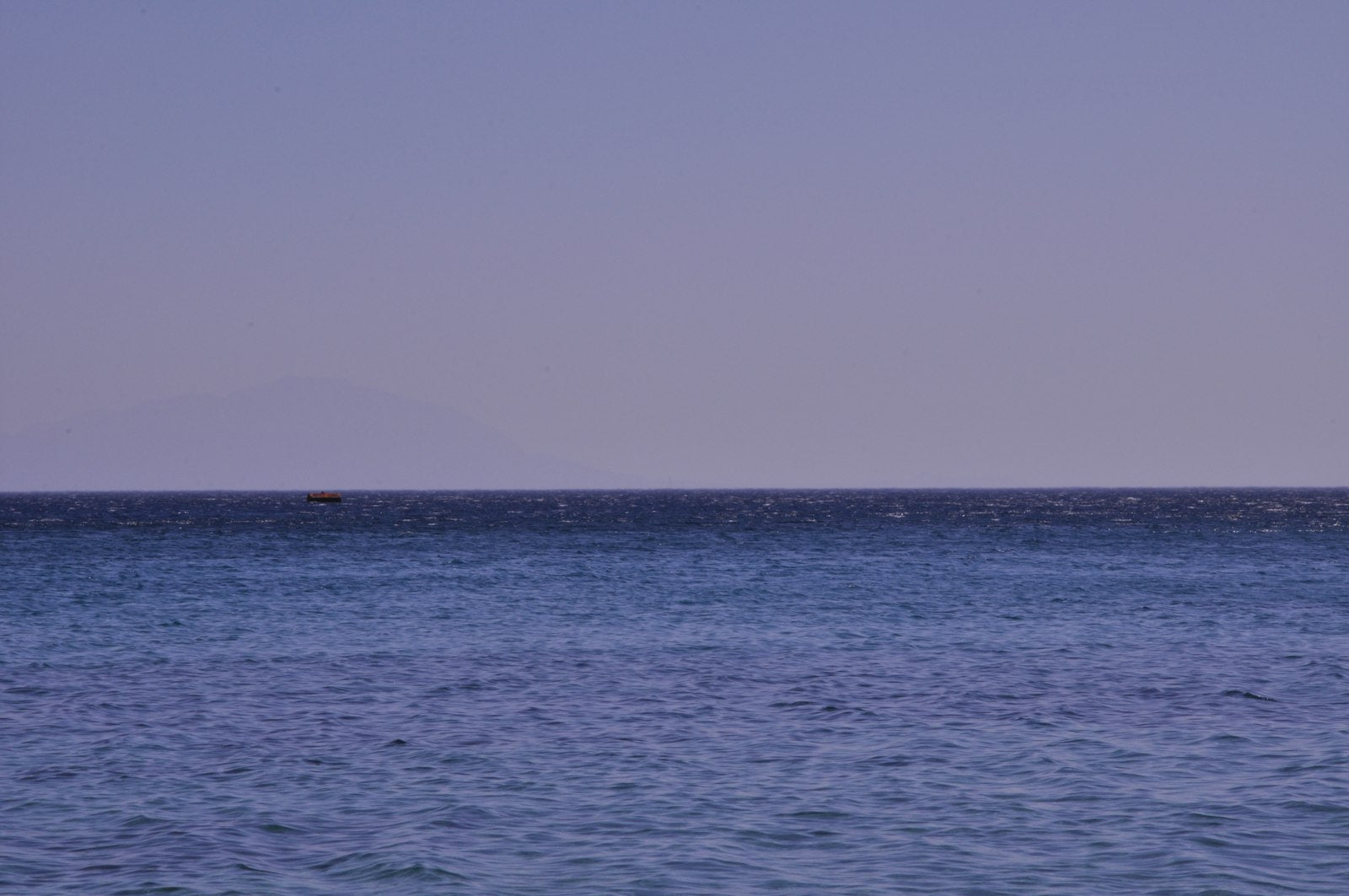 Open ocean water under a gray sky, horizon unbroken