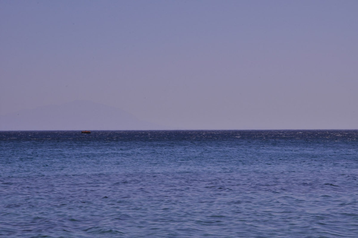 Open ocean water under a gray sky, horizon unbroken