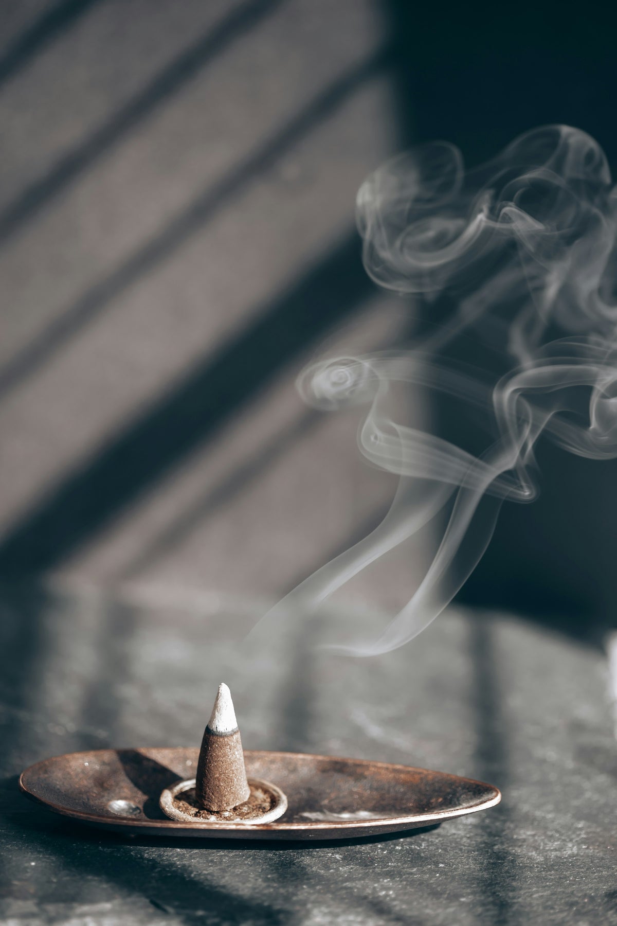 Incense smoke rising from a burner on a wooden table, used to clear negative energy from your home