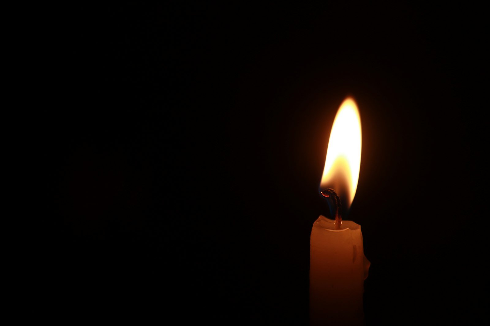 A single lit candle burning against a dark background