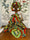 A handmade faceless Gullah doll in a bright wax print gown and matching headwrap, wearing cowrie shell earrings
