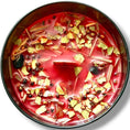 Load image into Gallery viewer, Top view of the deep red fiery wall candle dressed with protective roots, herbs, and stones
